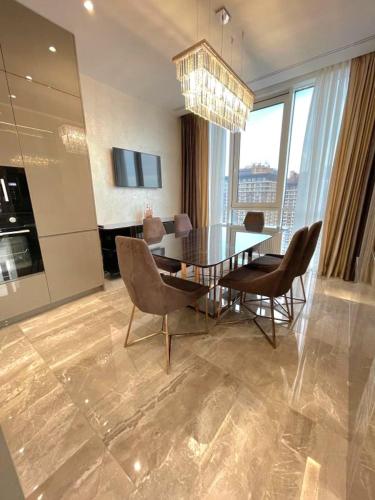 a dining room with a table and chairs and a chandelier at VIP Apartment 120m2 with Panoramic windows, 22 floor. OBOLON in Kyiv