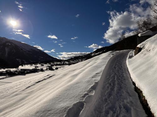 a snow covered road with the sun in the background at Casa Job - Gasthaus - Sauna, Whirlpool - Trun in Trun
