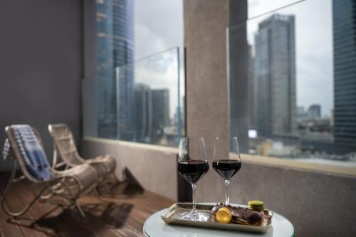 a table with two glasses of wine and a tray of food at Hotel Indigo Tel Aviv - Diamond District by IHG in Tel Aviv