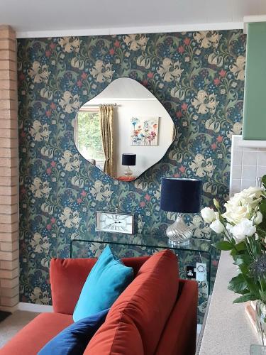 a living room with a red couch and a mirror at Willow Lodge Auchterarder in Auchterarder