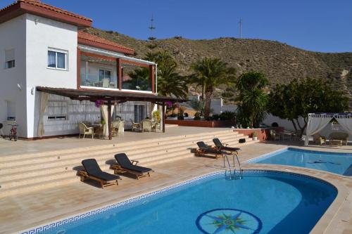 a swimming pool with chairs and a house at Villa Altavista El Campello, Alicante in El Campello