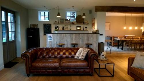 a brown leather couch in a living room with a bar at Muntershof in Velzeke-Ruddershove