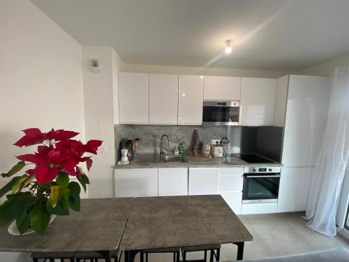 une cuisine avec des placards blancs et une table avec un vase de fleurs dans l'établissement Wonderful apartment near Monaco and the beach, à Roquebrune-Cap-Martin