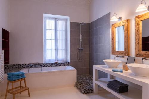 une salle de bain avec deux lavabos, une baignoire et une douche dans l'établissement Private Mansion, completely renovated with swimming pool, in historical center, à Arles