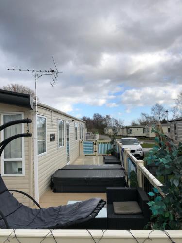 a large deck with a building and a house at Static Caravan with hot tub in Tattershall