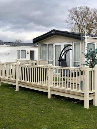 a mobile home with a wooden deck and a slide at Static Caravan with hot tub in Tattershall