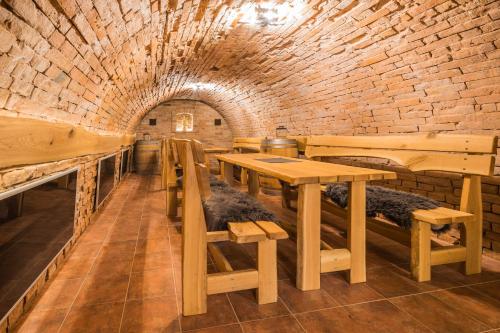 a restaurant with wooden tables and benches and a brick wall at Vinoza - ubytování a vinný sklep Velké Bílovice Rulandová in Velké Bílovice