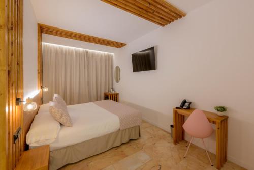 a bedroom with a bed and a desk and a television at Hotel Boutique Sibarys - Adults Recommended in Nerja