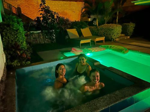 three women bathing in a swimming pool at night at Hostel las Palmas in Vilcabamba