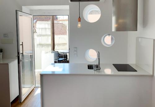 uma cozinha branca com um lavatório e um espelho em Casa Miradouro Apartments em Setúbal