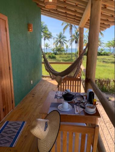 einen Tisch und Stühle mit einem Tisch und einer Hängematte in der Unterkunft Vila Budião - Corumbau in Corumbau