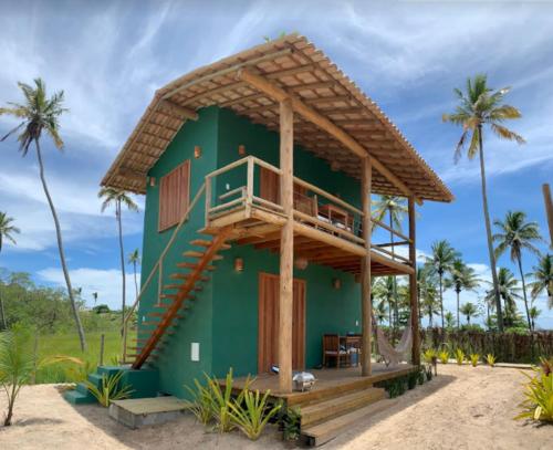 a green house with a balcony on a beach at Vila Budião - Corumbau in Corumbau