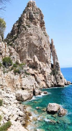 a mountain with blue water and a rocky shore at Sa Dommu 'e su coro in Triei