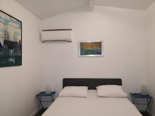 una camera con un letto bianco con due tavoli di La petite maison de Lingling a Mornas