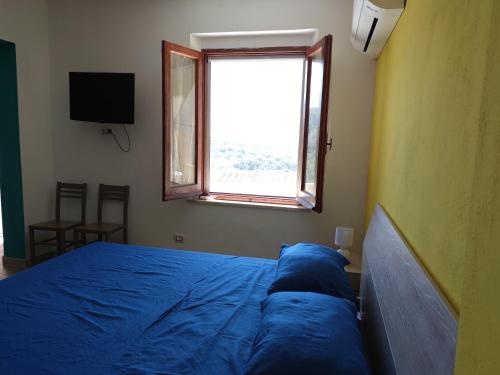 a bedroom with a blue bed and a window at Sa Dommu 'e su coro in Triei