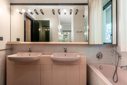 La salle de bains est pourvue de 2 lavabos, d'une baignoire et d'un miroir. dans l'établissement VILLA SISSI - PARADISO SULLE DOLOMITI, à Molveno