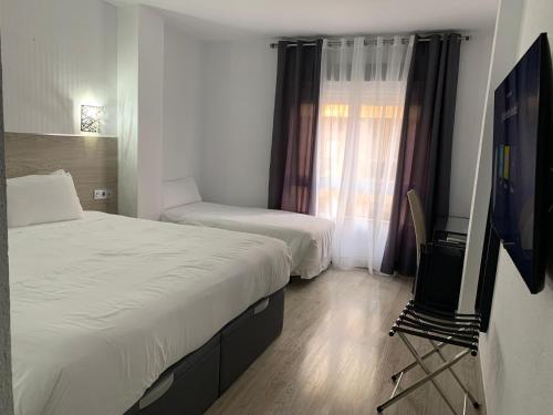 a hotel room with two beds and a television at Hotel Carlos III in Águilas