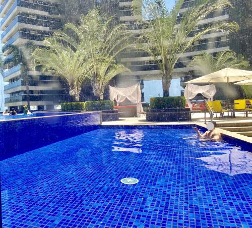 a large blue swimming pool next to a tall building at LANDSCAPE SOLAR - Beira Mar de Fortaleza in Fortaleza