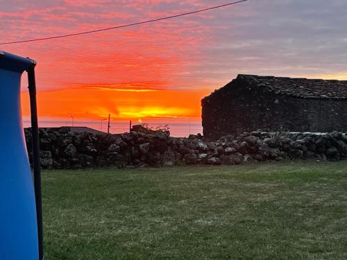 a sunset with a stone wall and a building at Spot Milasmar in Faja Grande