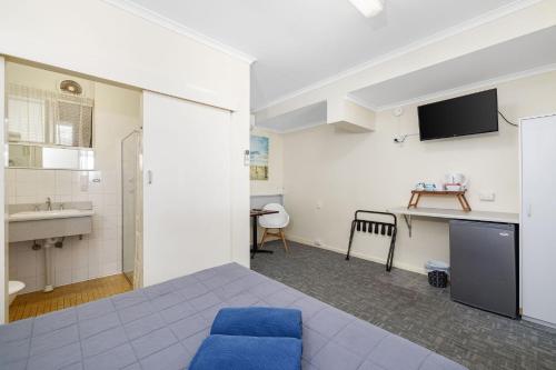 um quarto com uma cama, um lavatório e uma televisão em Navigators Motel em Port Lincoln