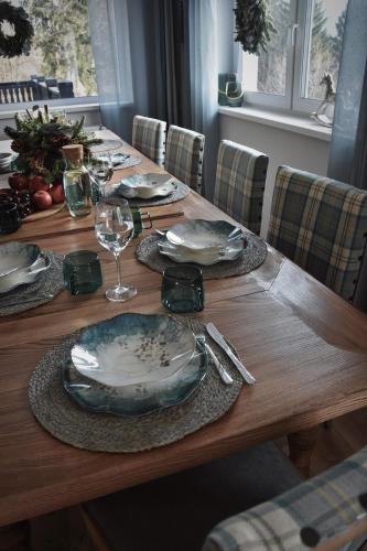 a wooden table with plates and wine glasses on it at Oto Widoki in Szklarska Poręba