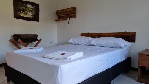 a bed with white sheets and towels on it at HOSTERÍA BRISAS DEL RÍO in Marinilla