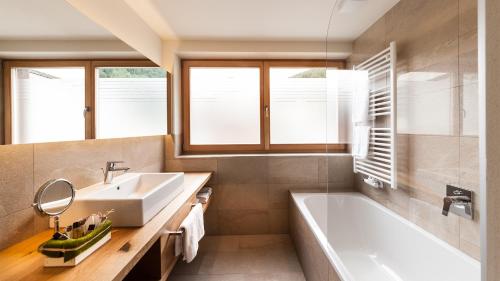 a bathroom with a white tub and a sink at Autentis in Rasùn di Sotto