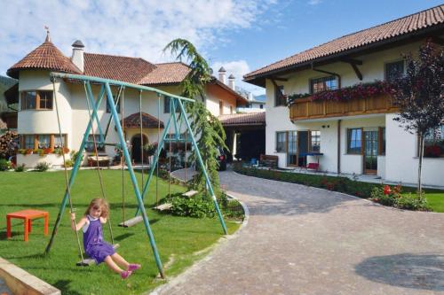 a little girl playing on a swing in front of a house at Apartment in Dolomites with Pool Access in Naz-Sciaves