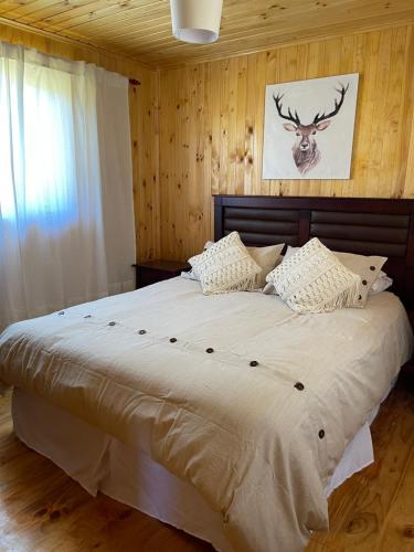 a bedroom with a large bed with a deer picture on the wall at Cabañas Kuela in Puerto Varas
