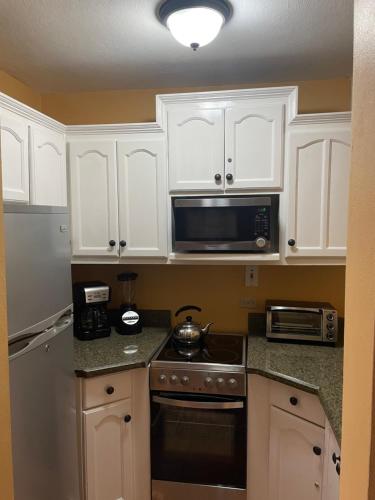 a kitchen with white cabinets and a stove and microwave at Castle by the Shore in Ocho Rios