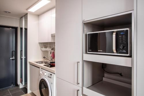 a kitchen with a microwave and a washer and dryer at Jeju Central Park Residence in Jeju