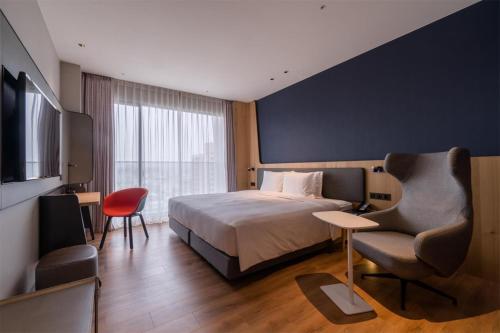 a hotel room with a bed and a chair at Holiday Inn Express Chiayi by IHG in Chiayi City