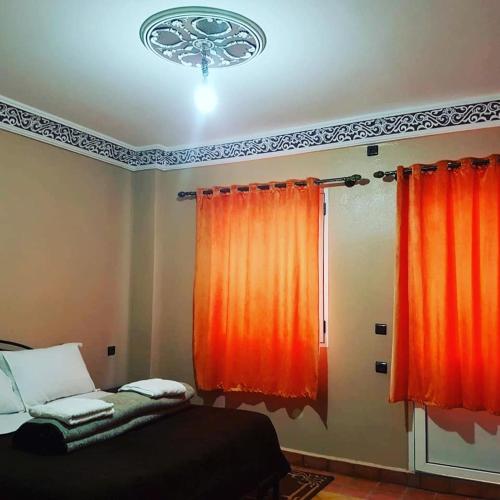 a bedroom with an orange curtain and a bed at Auberge Restaurant Fatihi Freres in Tinerhir