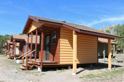 a small log cabin with a porch on a field at Eycat Lodging Company in Wapiti