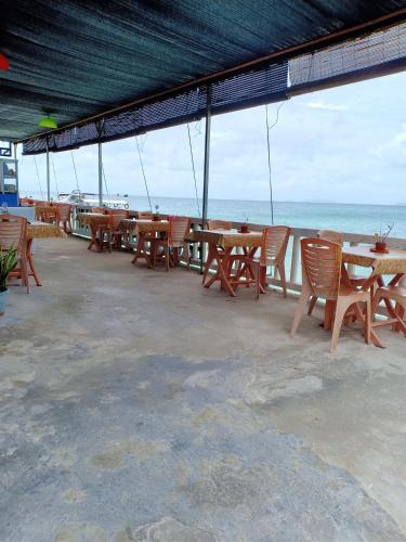 a row of tables and chairs with the ocean in the background at Suhaila Palace in Perhentian Island