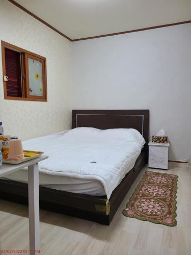 a bedroom with a bed with a table and a rug at Chenal Motel in Daegu