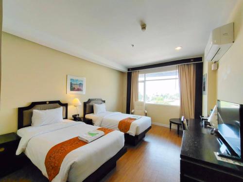 a hotel room with two beds and a flat screen tv at Wangchan Riverview in Phitsanulok