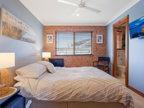 a bedroom with a bed and a brick wall at Grand Pacific 2 Unit 4 -Omaroo - First Floor in Narooma