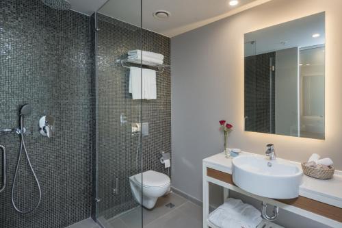 a bathroom with a toilet, sink, and shower at Leonardo Plaza Netanya Hotel in Netanya