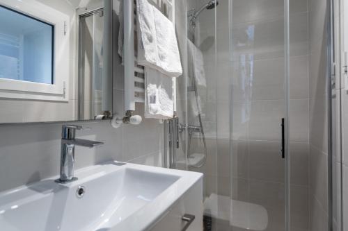 La salle de bains blanche est pourvue d'un lavabo et d'une douche. dans l'établissement Lugar especial, gran patio, junto al ayuntamiento, à Bilbao