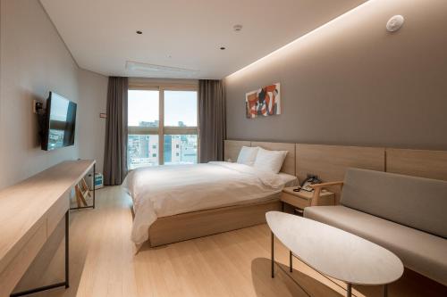 a hotel room with a bed and a couch at Chestertons Sokcho in Sokcho