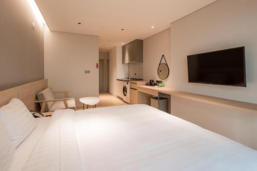 a hotel room with a white bed and a flat screen tv at Chestertons Sokcho in Sokcho
