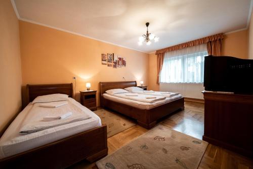 a bedroom with two beds and a television in it at Lilla Apartments in Odorheiu Secuiesc