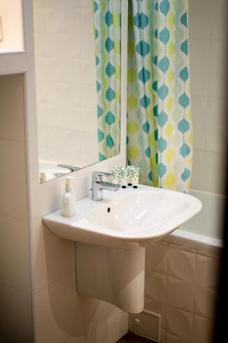 a bathroom sink with a mirror and a shower curtain at Lilla Apartments in Odorheiu Secuiesc