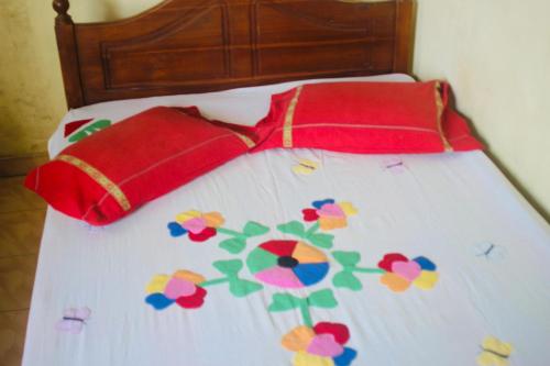 a bed with two red pillows with flowers on it at Sunshine Guest in Madihe East