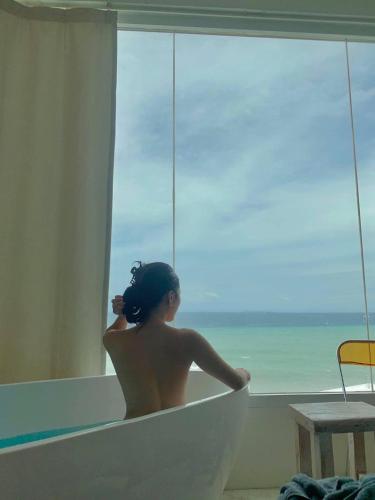 a woman sitting in a bath tub looking out of a window at Sugarsea Inn & Dive shop in Mactan