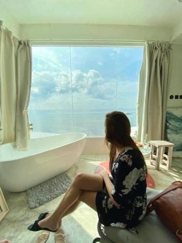 a woman sitting in front of a bath tub in a bathroom at Sugarsea Inn & Dive shop in Mactan