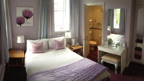a bedroom with a large bed with pink pillows at Lauren House in Dumfries