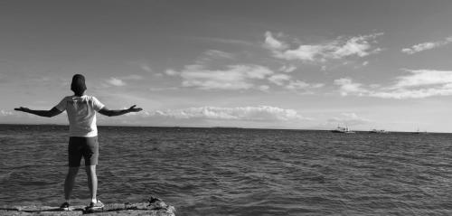 a man standing on a rock in the ocean at Sugarsea Inn & Dive shop in Mactan