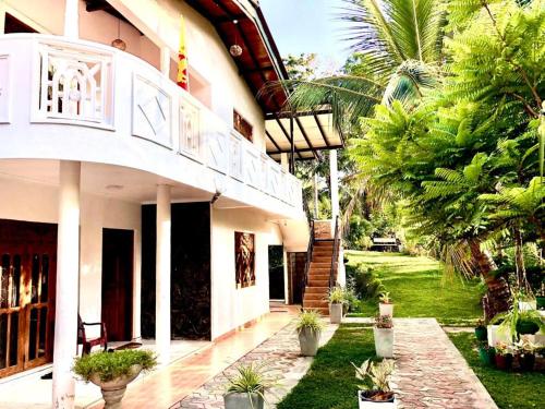 a house with a balcony and a yard with palm trees at Thusitha s nest in Dickwella